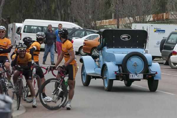 Riders from the Malaysian National Team observe a vintage car pass by in Echuca before the start to stage one.