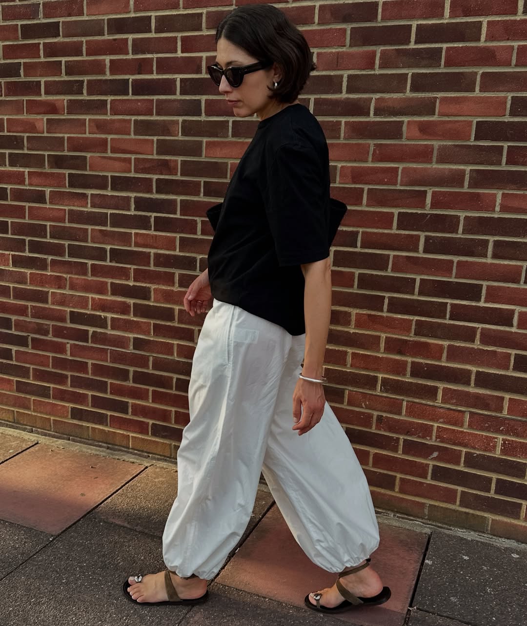 Lucy in white cotton trousers and sandals
