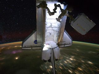 Backdropped by a night time view of the Earth and the starry sky, the Space Shuttle Endeavour is photographed docked at the International Space Station on May 28, 2011. The STS-134 astronauts left the station the next day on May 29, after delivering the A