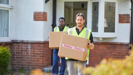 Two removal men carrying boxes