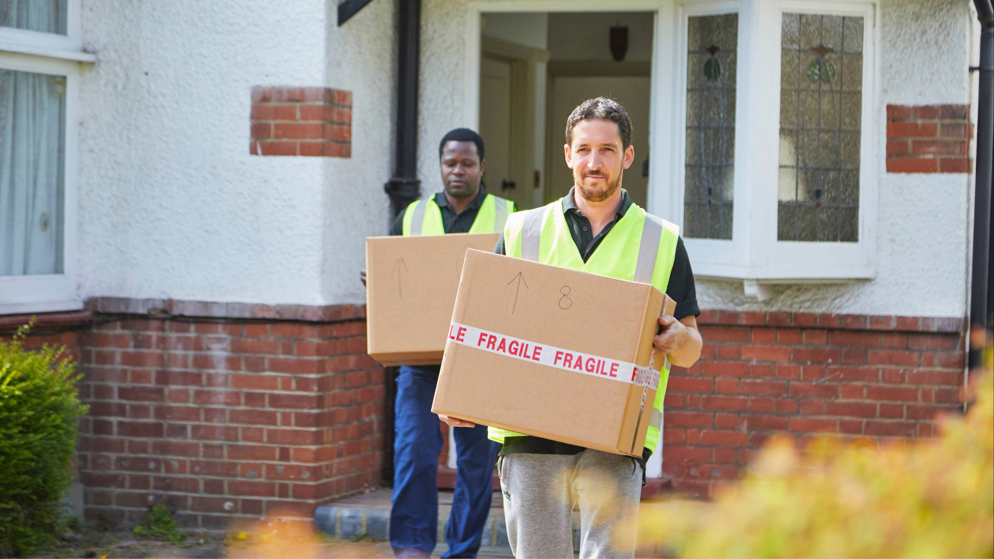 Two removal men carrying boxes
