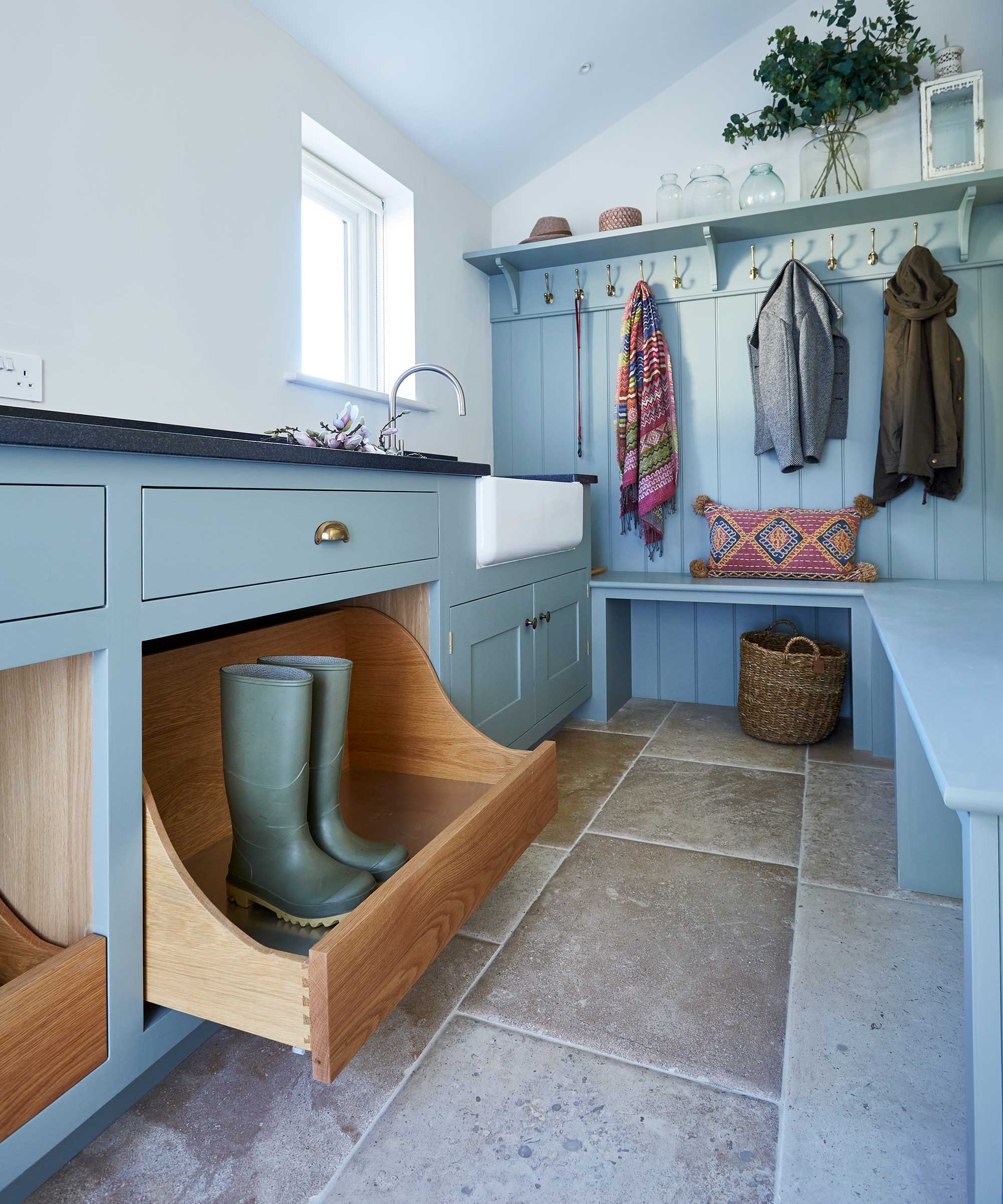 blue boot room with pull-out storage and stone flooring