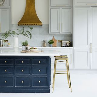 white kitchen cabinets and flooring with dark blue island with drawers and gold stools