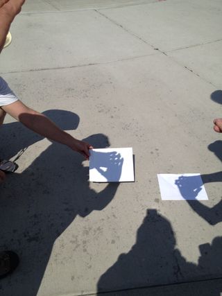 During total eclipse, participants use their hands to observe crescent shapes on the ground.