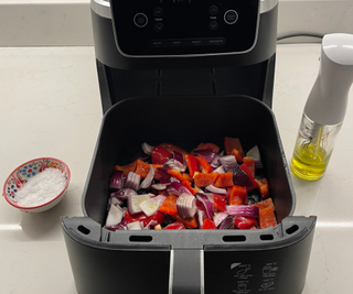 The Ninja Air Fryer Pro is ready to cook my diced vegetables, with a glass spray oil bottle and salt pinch bowl on the side