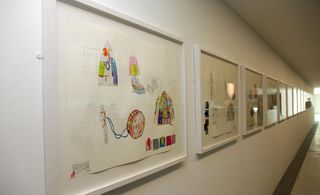 Ink and pencil storyboards are framed on the wall. It shows different characters.