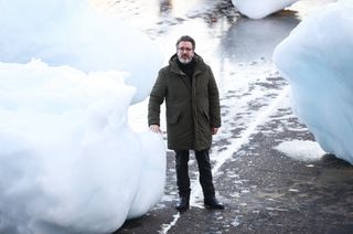 Artist standing next to large ice block