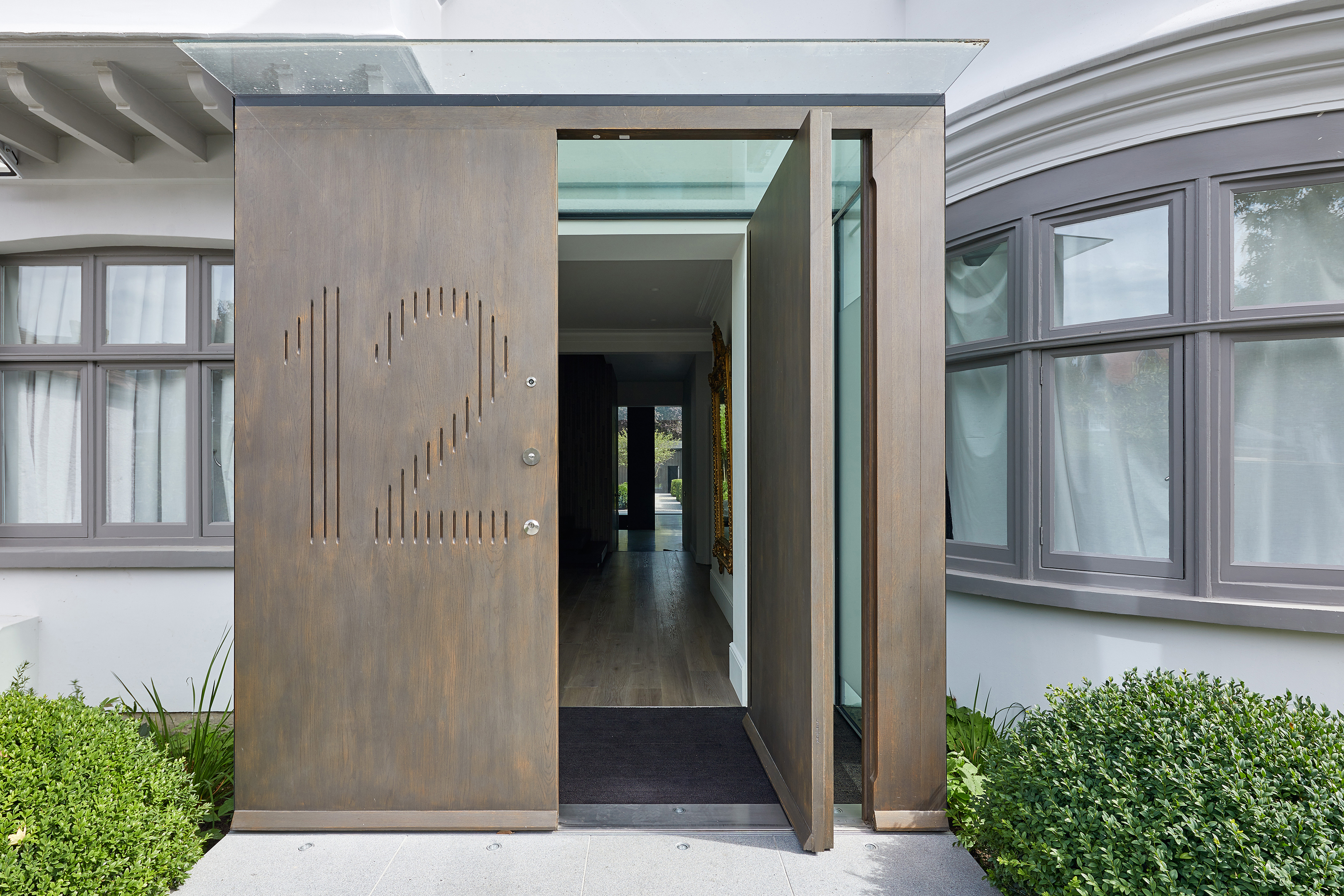 Create a grand entrance with a frameless glass box completed with a smart bespoke door. Raw E80 pivot door set and matching boarded panel, in European oak with stained Onyx metallic finish and number engraving, H2.4m x W2m, from £20,000 + VAT, Urban Front. [inc VAT £24,000]
