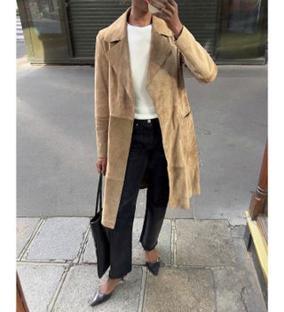 Sylvie wears black jeans, pointed toe heels, white sweater, and light brown suede jacket.