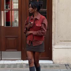 @_livmadeline wears a rust shirt, matching knitted vest, checked skirt and knee boots