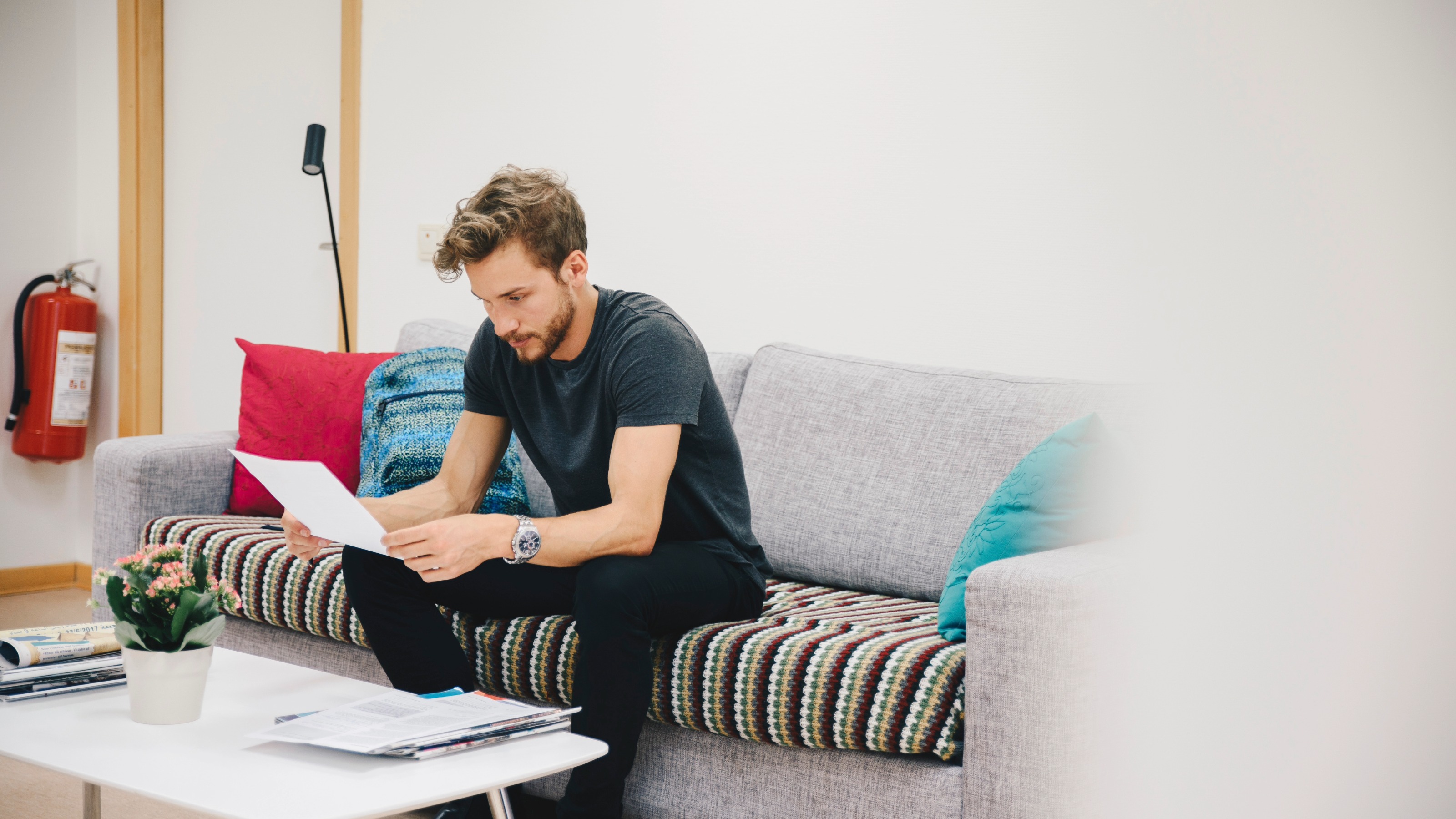 Young male patient reading document while sitting on sofa in waiting room