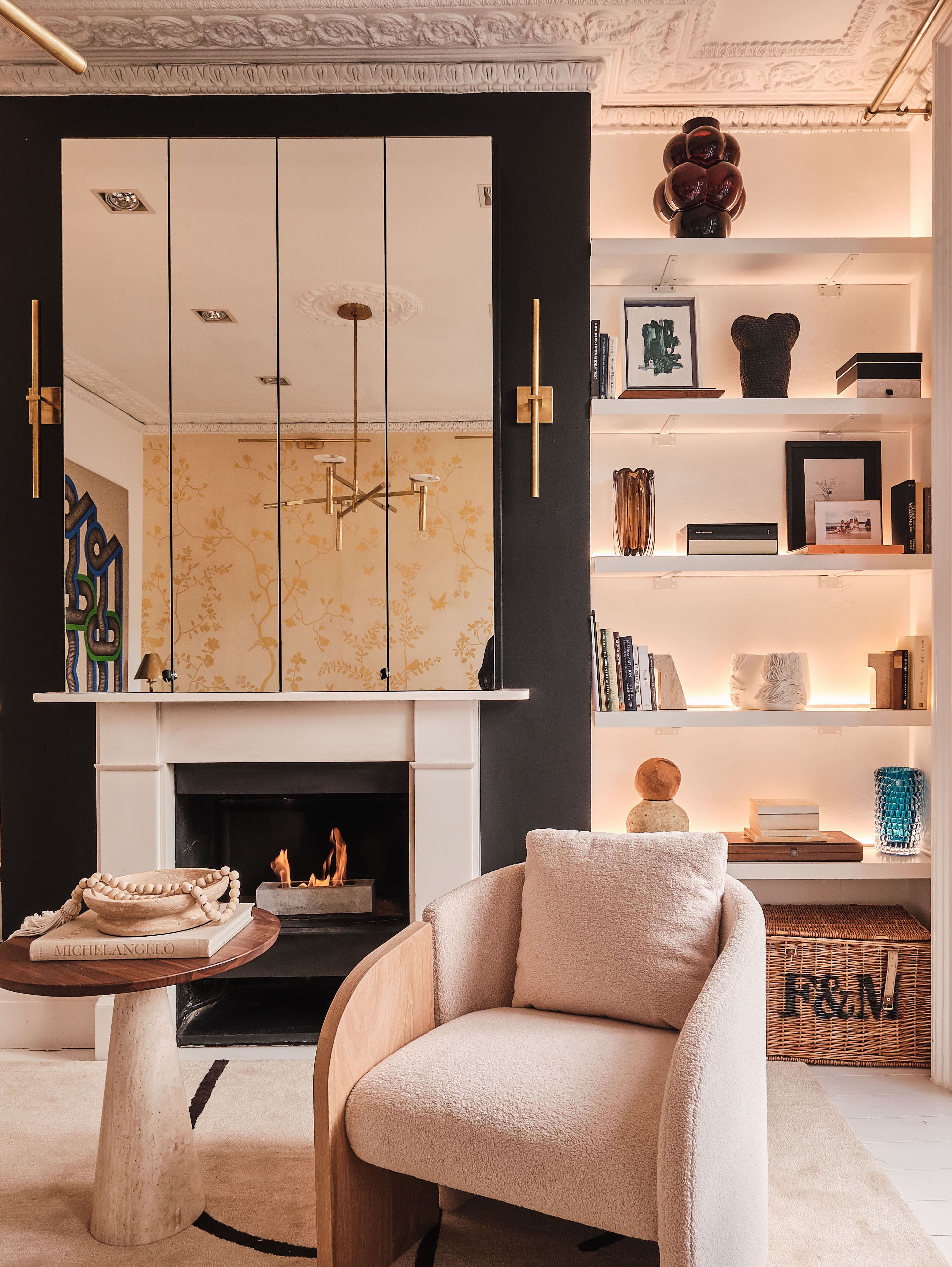 A living room with a built in fireplace, with shelves designed next to it, lit up with recessed lights