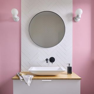 pink wall with wash basin and mirror on wall