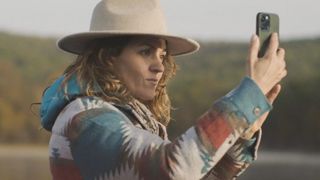 Woman using phone to take picture in a field