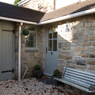 home exterior with stone wall and bench