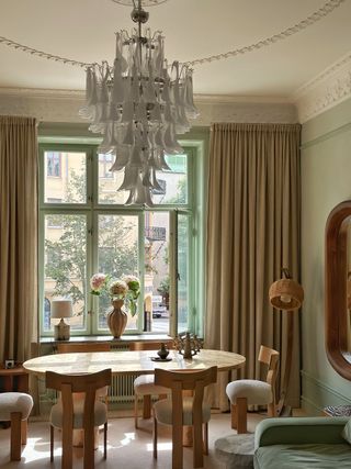 a dining table with a flower murano glass chandelier above it