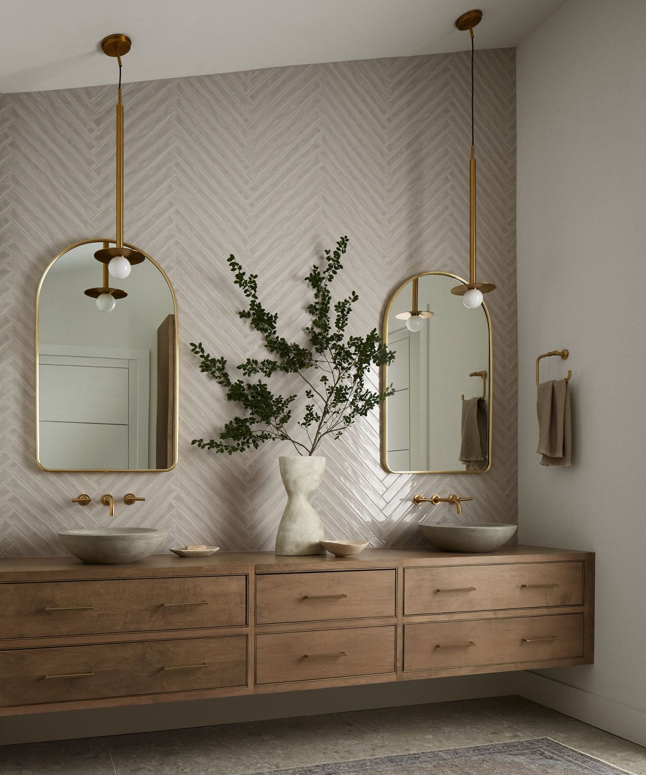 A coastal modern bathroom with tiled walls, wooden cabinetry, and two gold mirrors