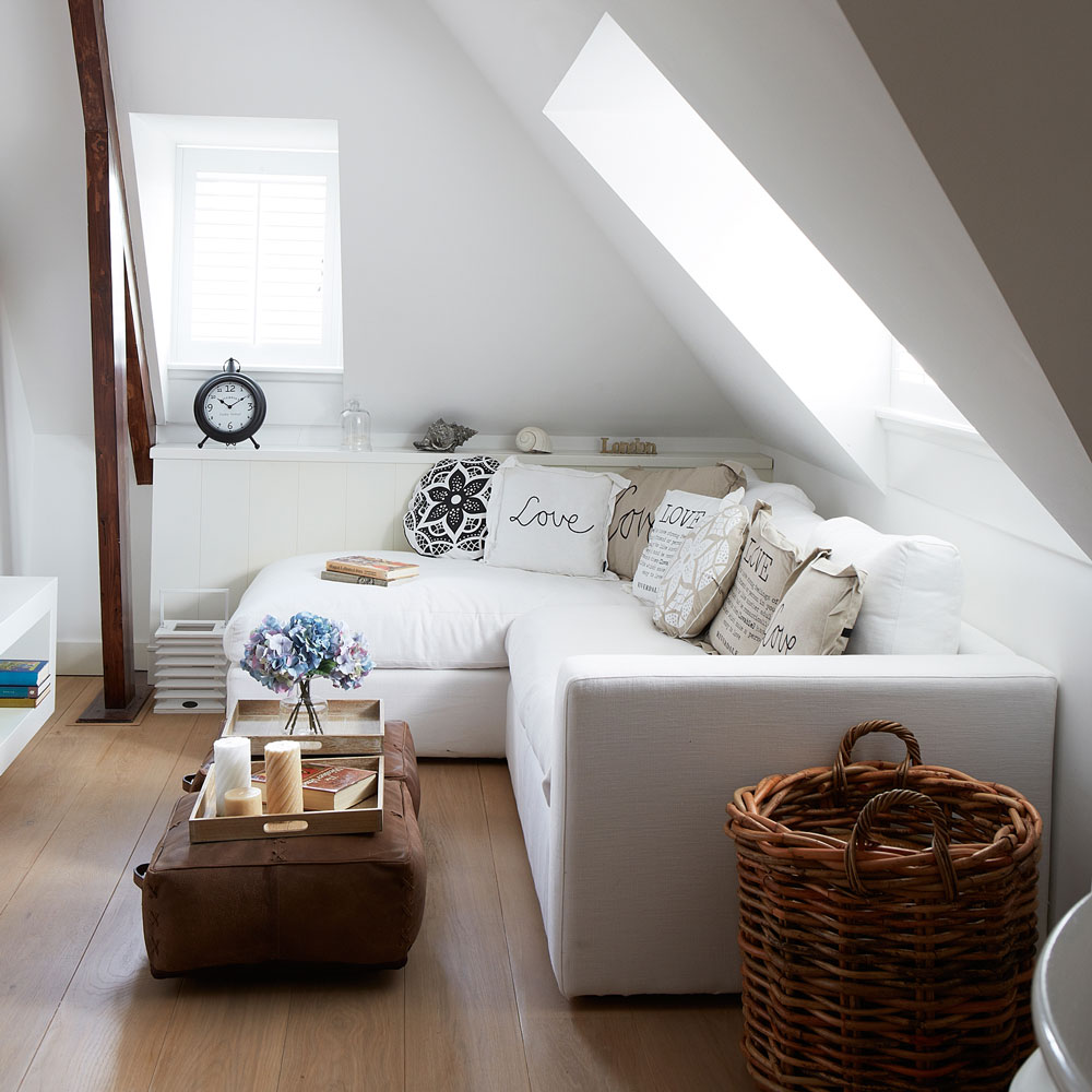 white living room with white l shaped sofa and cushioned coffee table on top of a wooden floor