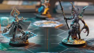 Two models (an Ioneth Deepkin to the left and a Slaanesh daemon to the right) stand opposite each other on the Warhammer Underworlds: Deathgorge board