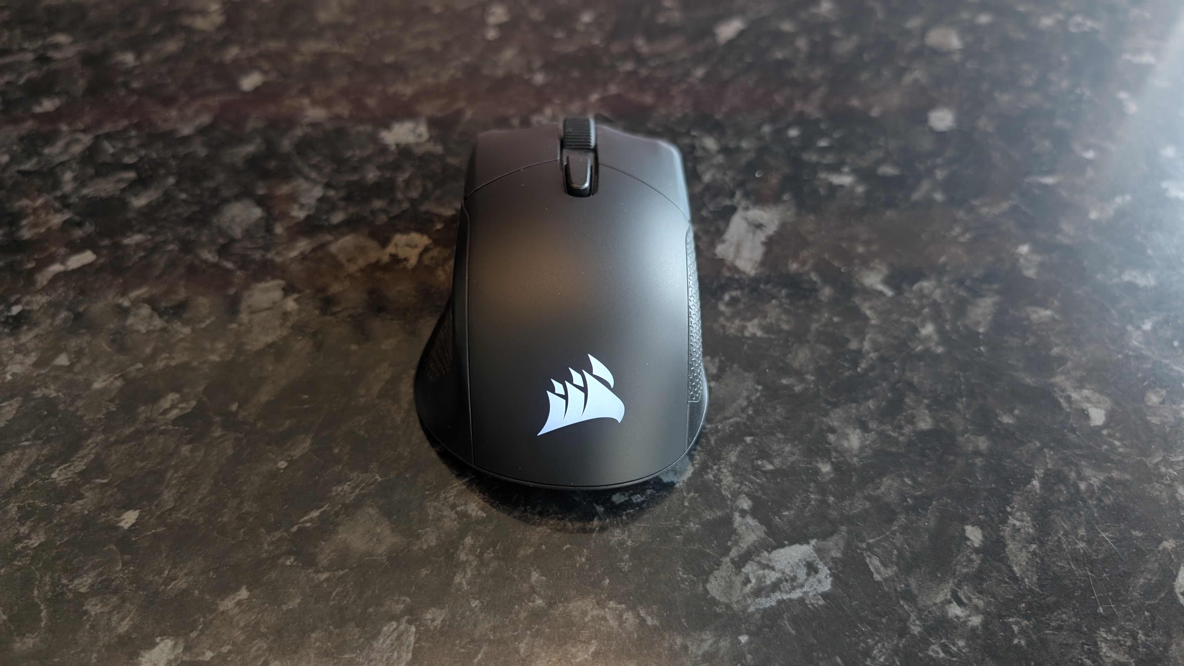 The Corsair Harpoon V2 Wireless gaming mouse pictured on a dark marble worktop.