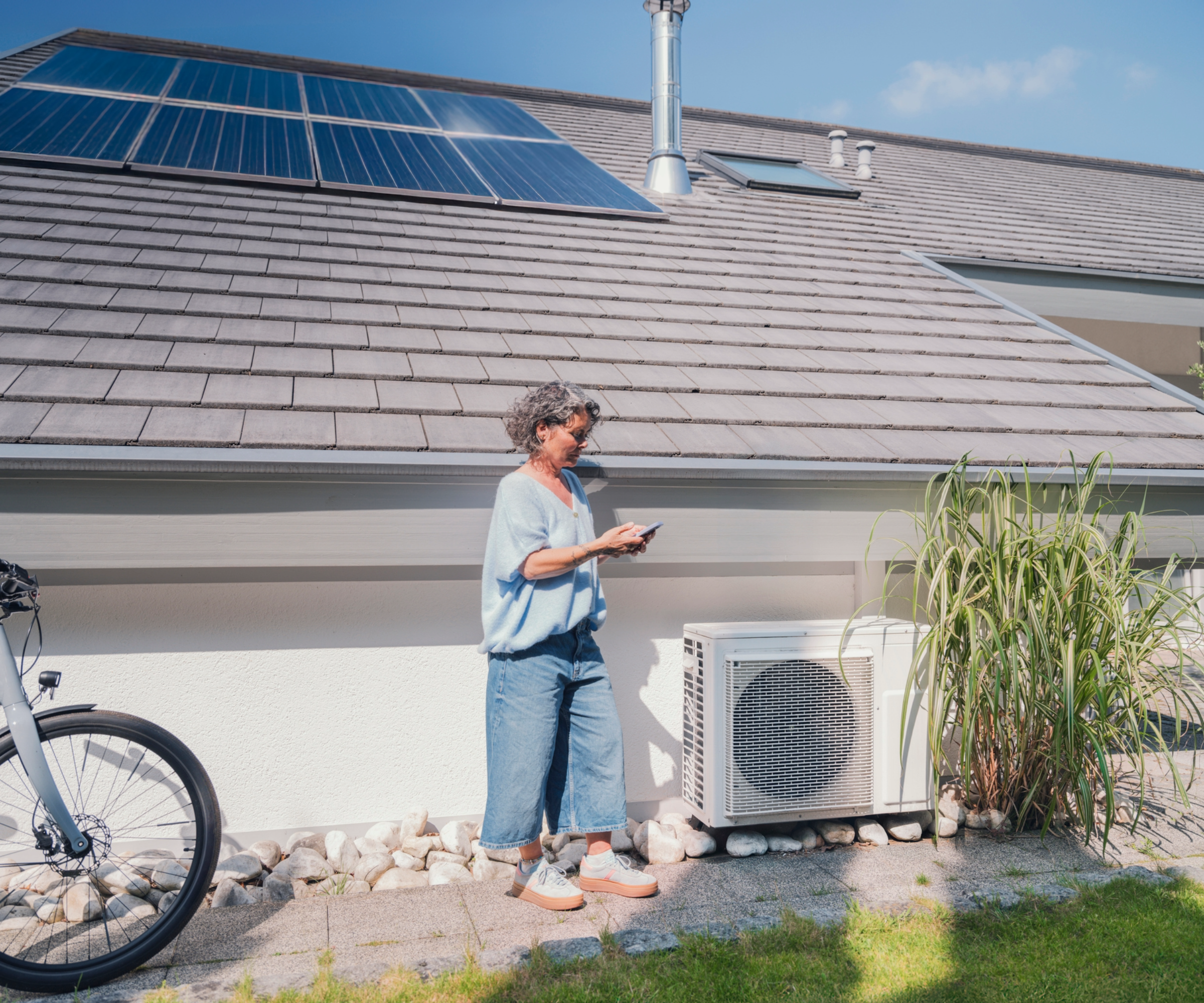 Woman standing next to a heat pump near a house