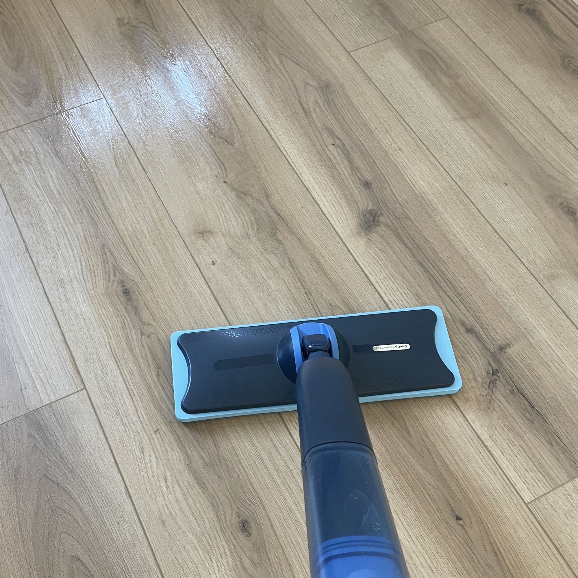 Philips OneUp Electric Mop cleaning oak-coloured wood-effect flooring, with a slight sheen from where the planks have been cleaned