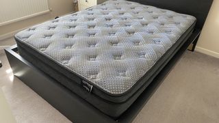 The Dreamstage Value Quilted Hybrid Mattress by Diamond mattresses, on a bed frame in our reviewer's bedroom as she prepares to test it