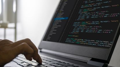 A hand typing lines of code on a laptop