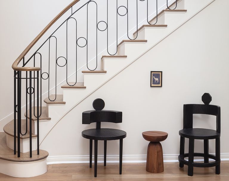 wrought iron staircase with curved balustrade and modern black chairs