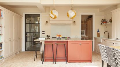 Cream kitchen with orange kitchen island by Olive & Barr