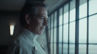 Ben Mendelsohn as Orson Krennic standing in front of a window on Andor Season 2