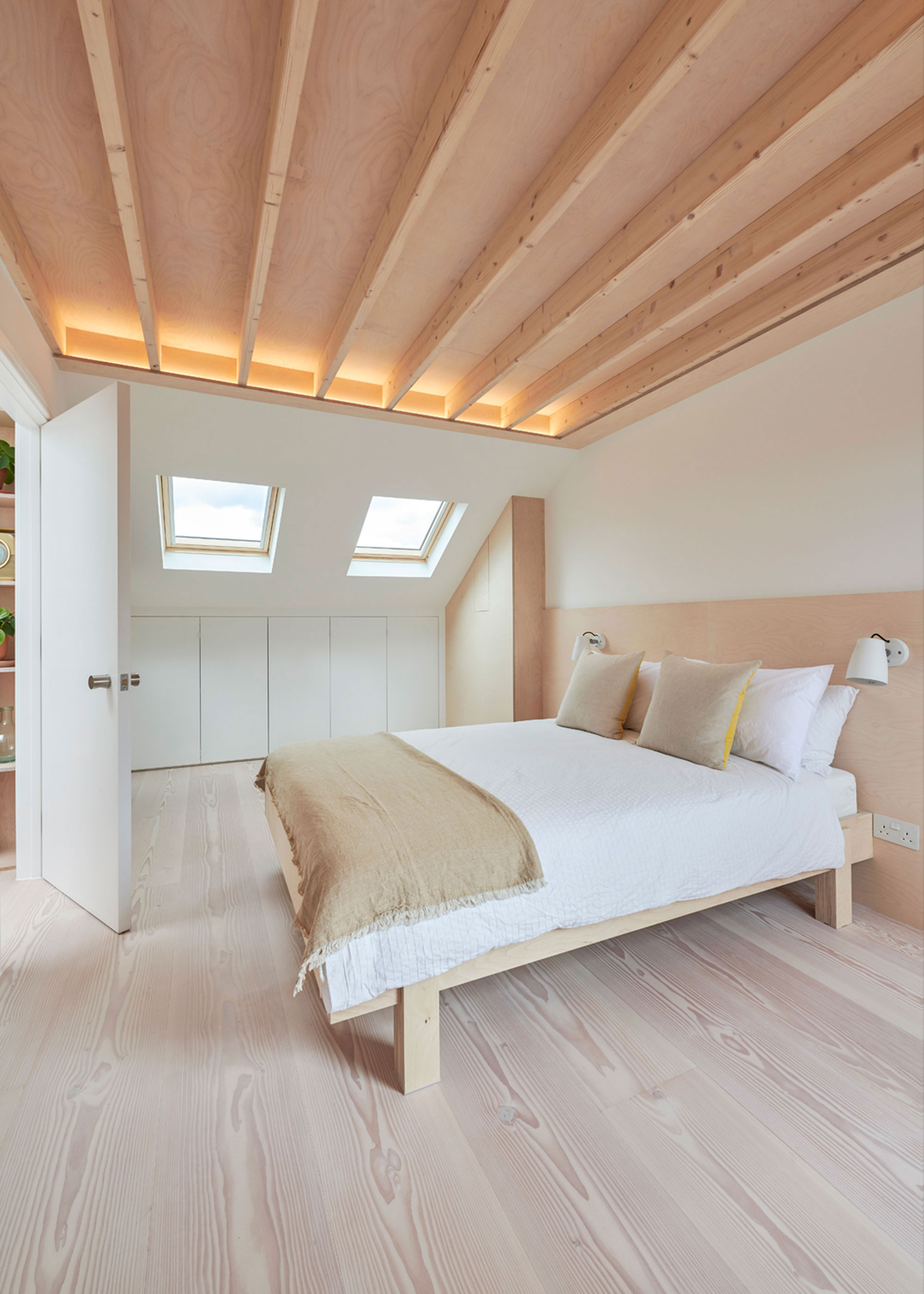 modern loft conversion bedroom with skylights and wooden flooring and under eaves storage