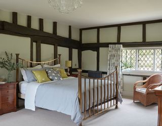 iron bed in beamed bedroom with leaded windows