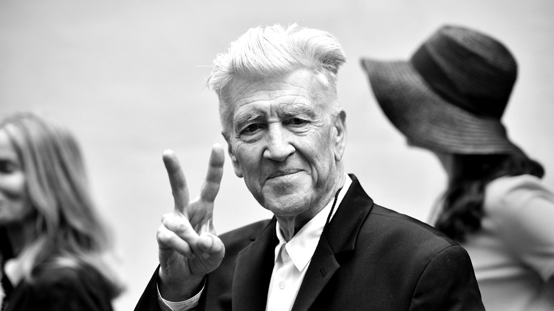 a man in a suit gives a peace sign to a camera