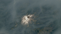 A volcano emerging from a blanket of smoke.
