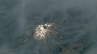 A volcano emerging from a blanket of smoke.