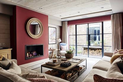 Red living room with red chimney breast, neutral alcoves, and neutral flooring and upholstery