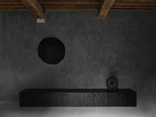 At Faina gallery, a black round tapestry hangs on the grey wall over a low black cupboard