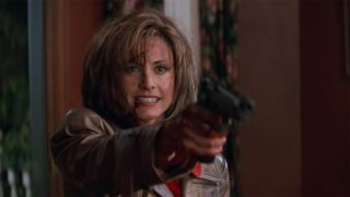 Courteney Cox as Gale Weathers holding a gun in Scream