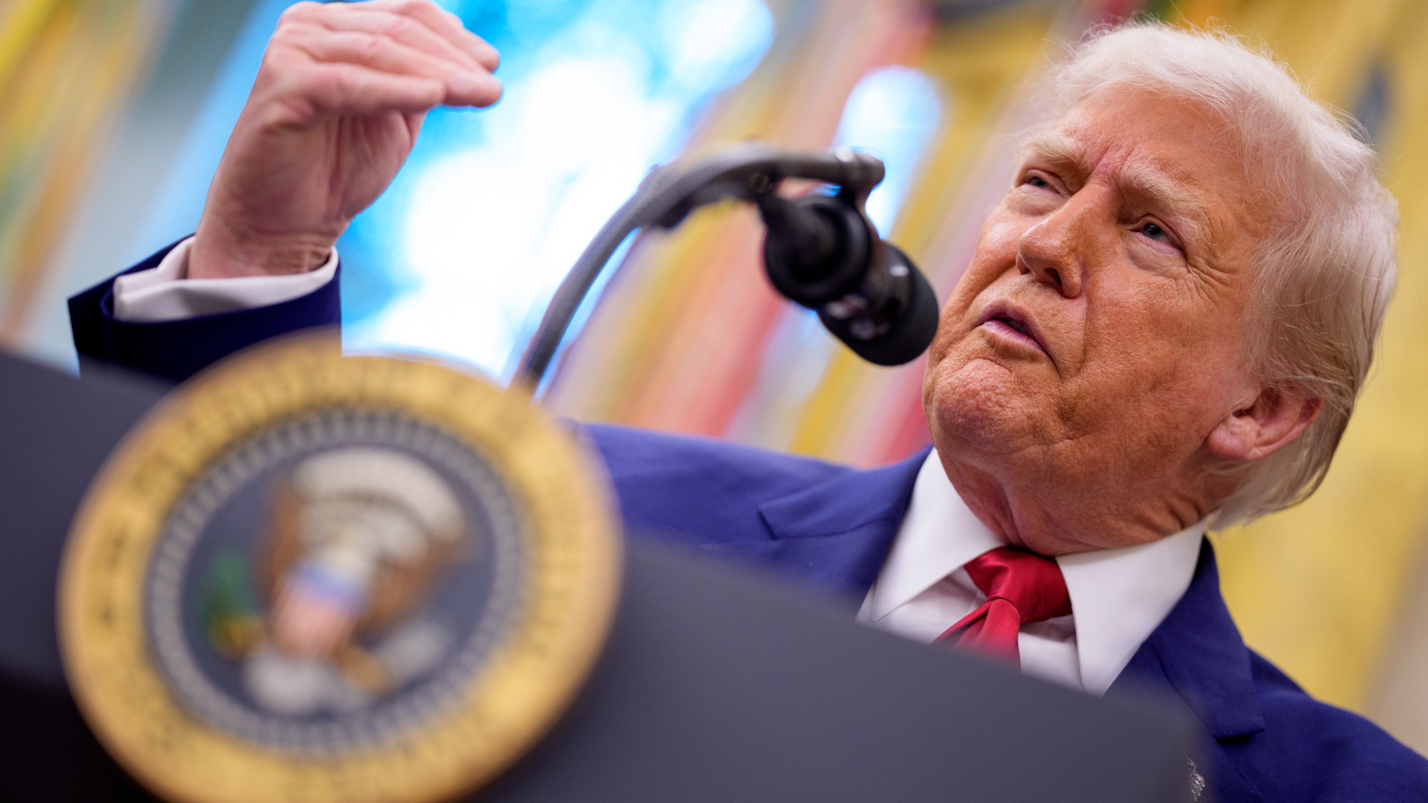 President Trump talking into a microphone while stood at a podium