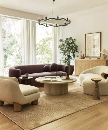 Curved purple sofa with curved neutral armchair, coffee table, curved candlestick holder and candelabra