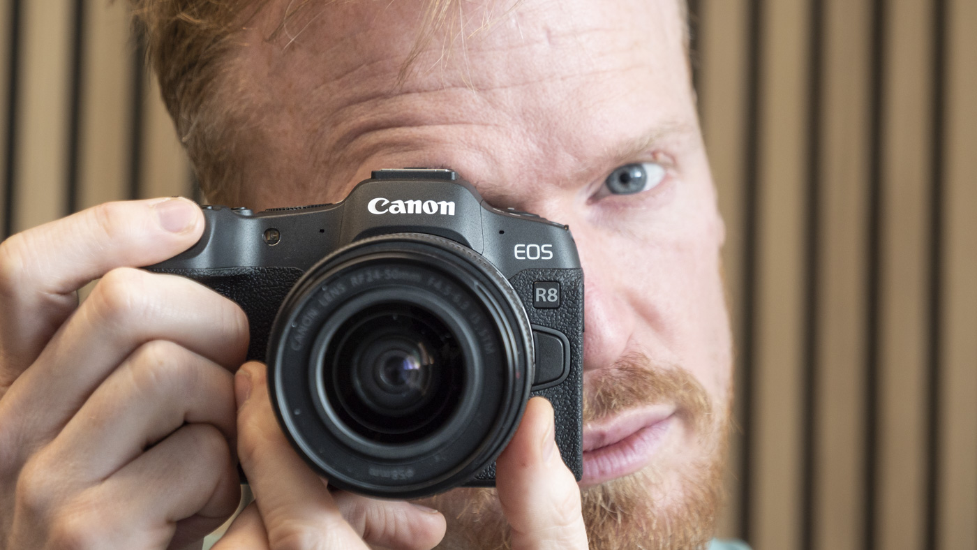 Canon EOS R8 and photographer looking into viewfinder