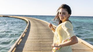 Beautiful women is running on a very long jetty while sunrise leading into a red sea reef.