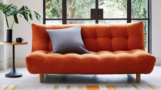 A bright orange sofa bed in a contemporary living room