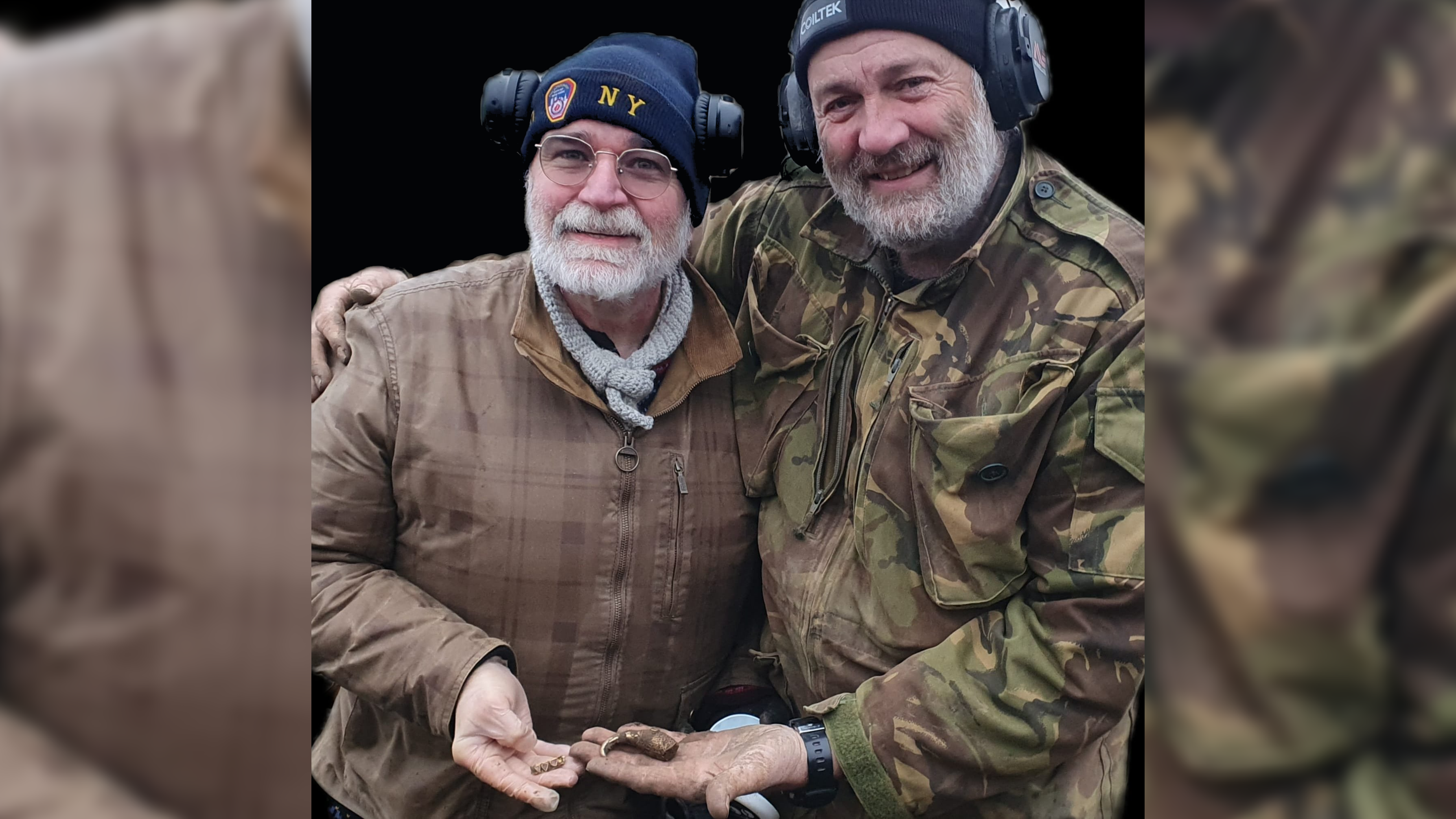 Two older white men with beards and rugged jackets hold the small gold artifacts they recovered while metal detecting.