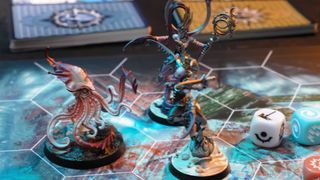 A squid miniature stands beside two Slaanesh daemon models on the Warhammer Underworlds: Deathgorge board