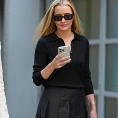 Woman in knit top and skirt looking at a phone