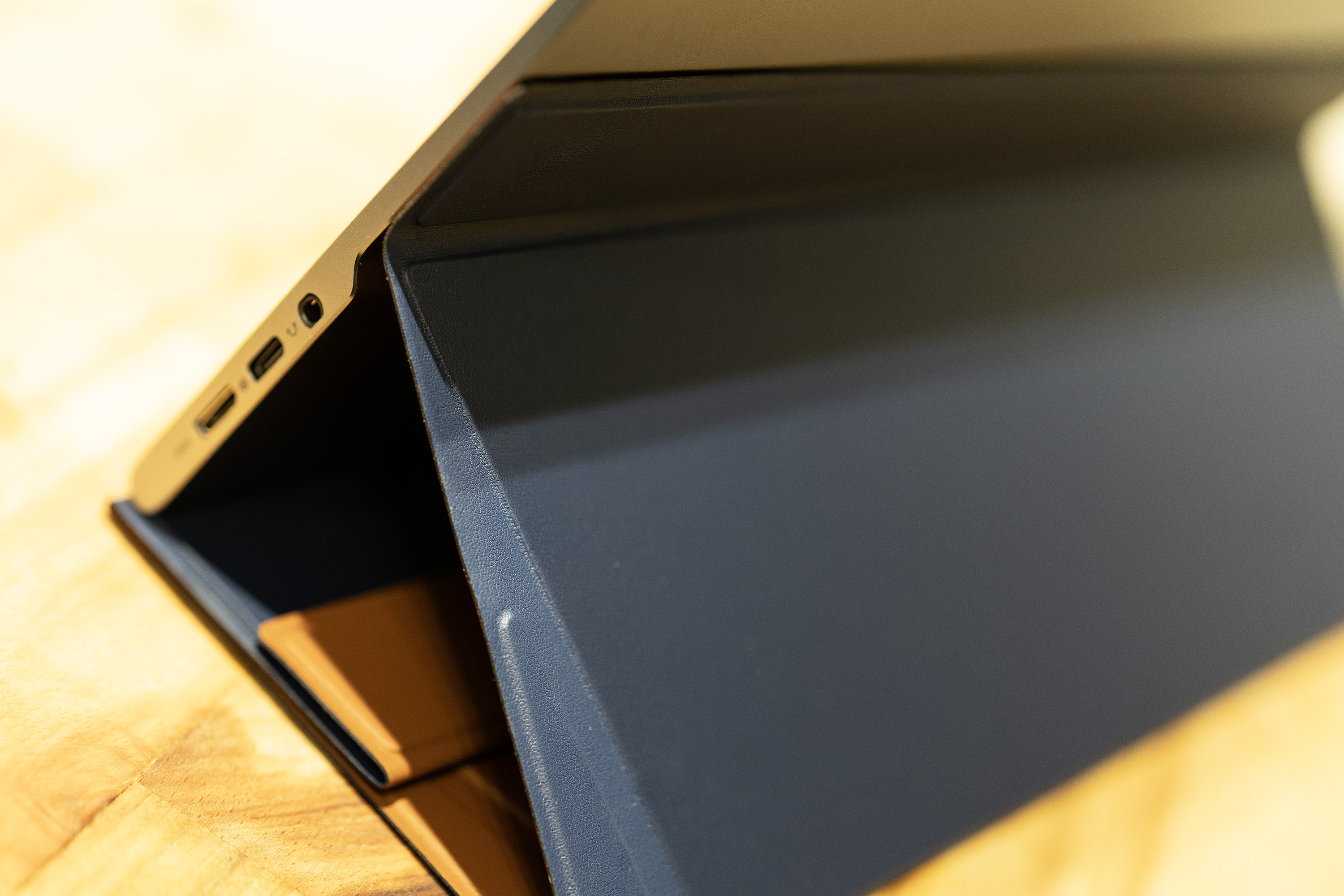 A black and silver ASUS ZenScreen MQ16AH portable monitor on a wooden brown desk