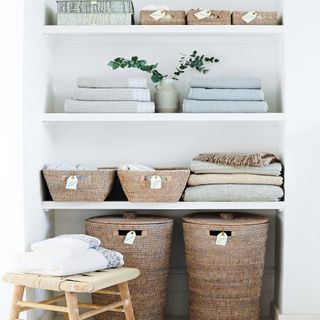 white shelves with storage baskets and throw blankets and a wooden stool