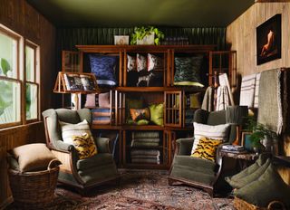 A furniture store's room is stuffed in plush furniture items such as upholstered armchairs, wood cabinets filled with pillows and other textiles, carpets, and more.